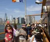 Tourists on a boat are taking photos and enjoying the view of a city skyline on a clear day