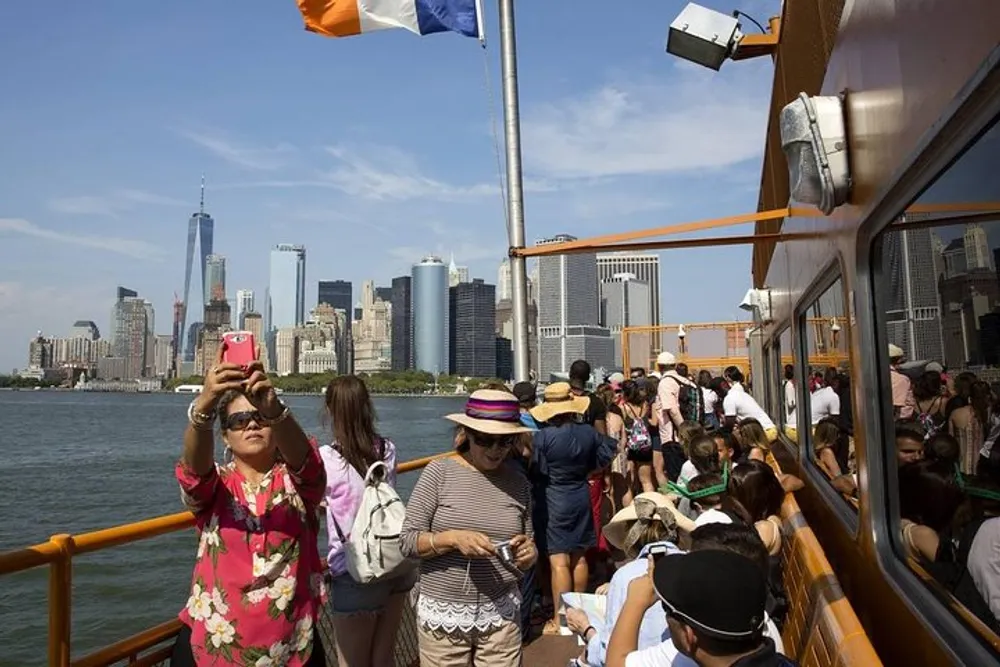 Tourists on a boat are taking photos and enjoying the view of a city skyline on a clear day