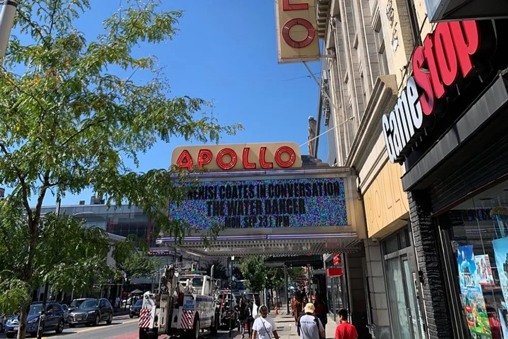 The image features a sunny day on a city street with pedestrians and the iconic Apollo Theater marquee in the background