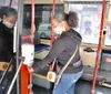 A person is using a hand sanitizer dispenser on a public bus while wearing a face mask