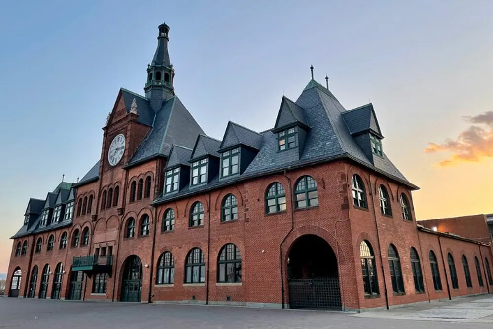 The image captures a historic red brick building with a clock tower under a dusk sky