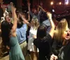 A lively group of people is celebrating and raising their glasses in a bar with live music