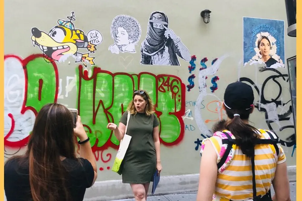 A group of people is engaged in a tour observing and possibly discussing the colorful street art and graffiti on an urban wall