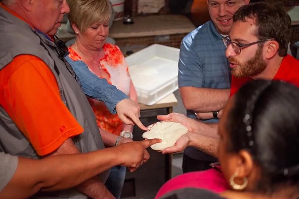 A group of people is engaged in an interactive activity passing around what appears to be a soft material possibly dough while focusing their attention on it