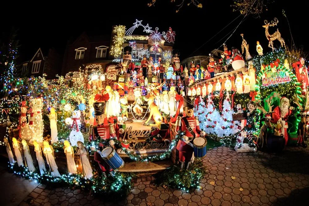 The image shows a house extravagantly decorated with a variety of illuminated Christmas decorations including Santa Claus figures reindeer lights and festive ornaments